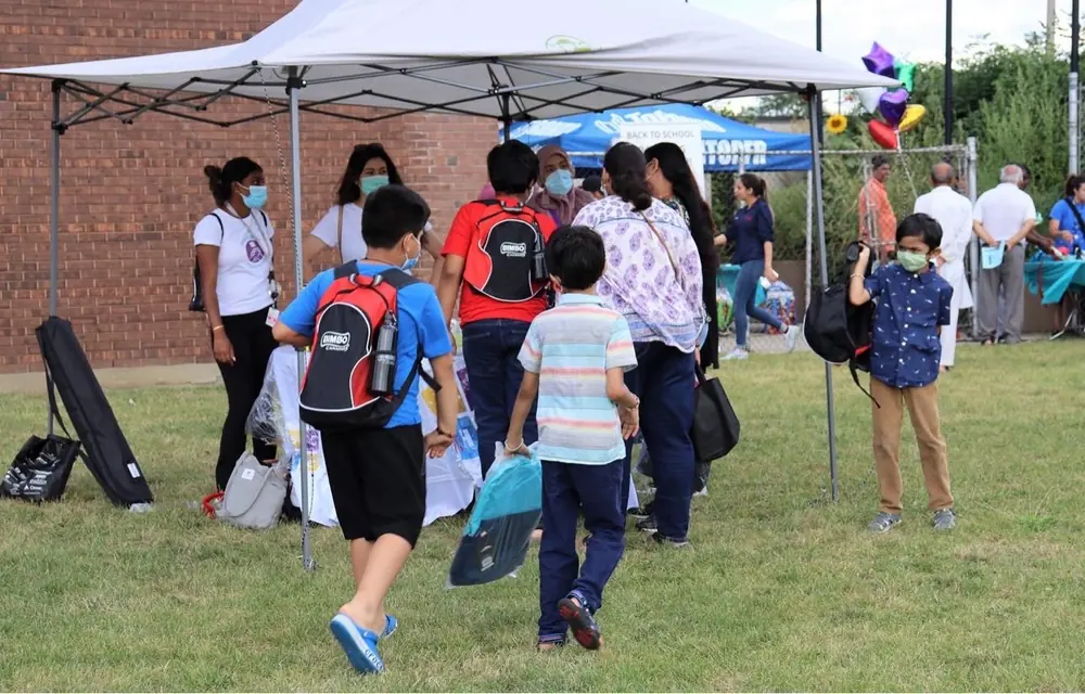 Children carrying new backpacks across the grass at a Back to School event in Scarborough