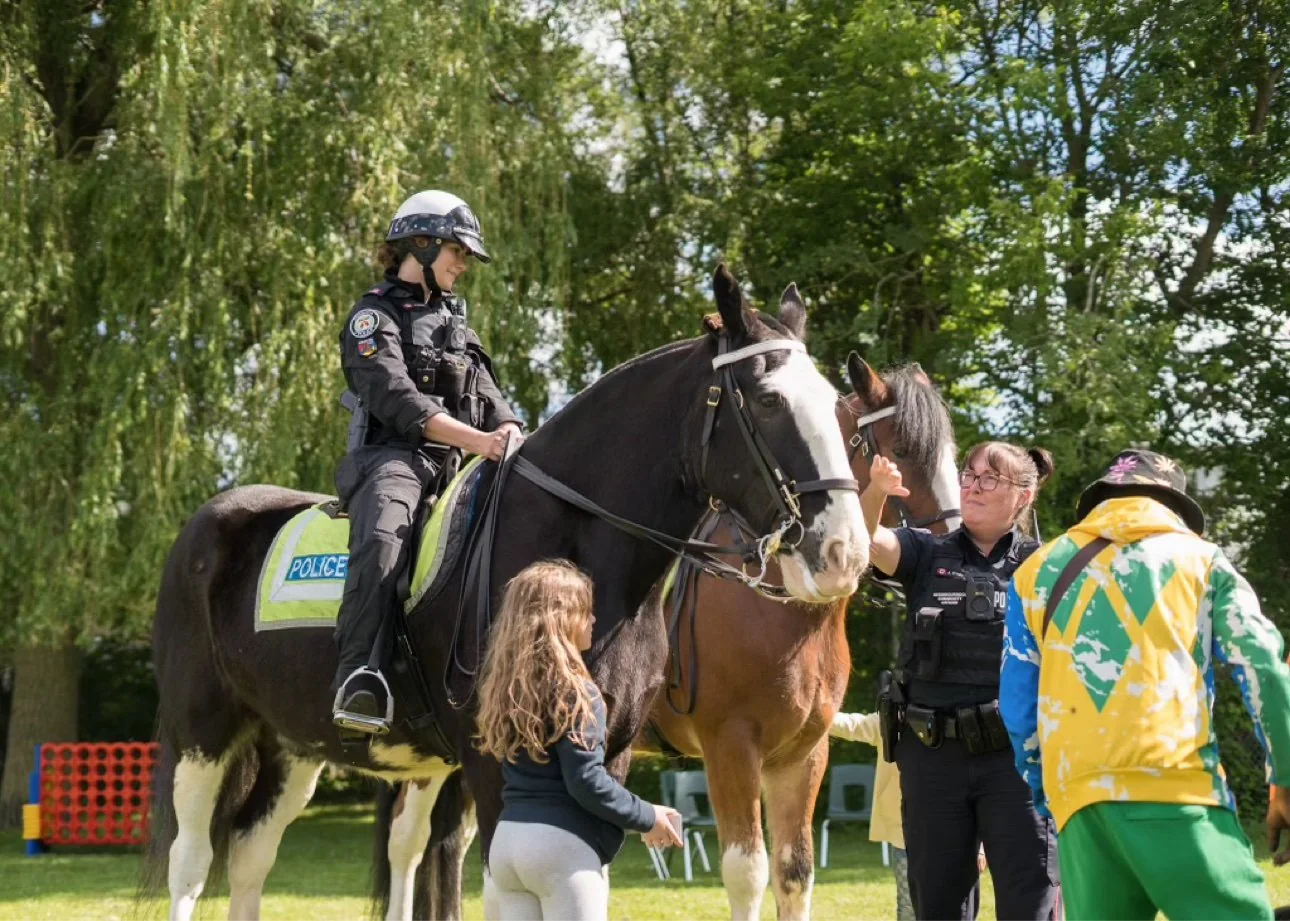 Children meeting Toronto Police Service mounted unit officers and their horses at an outdoor community event