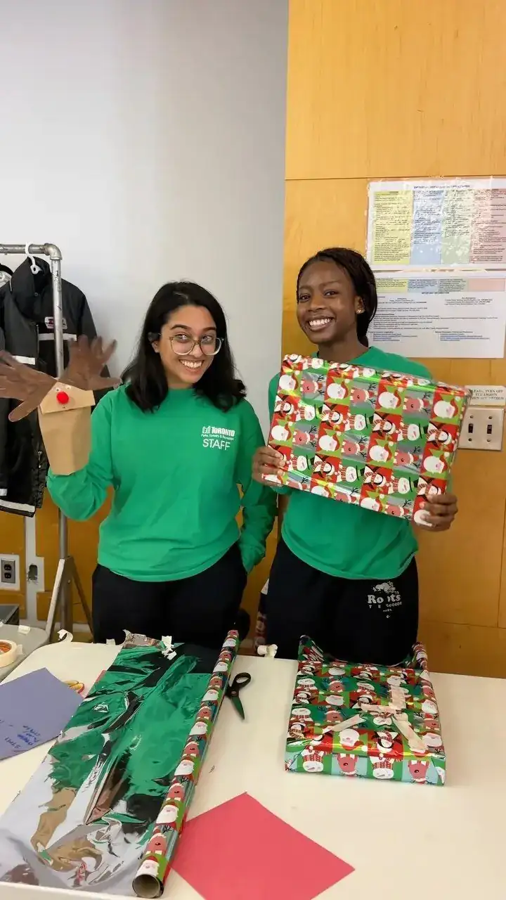 Two volunteers wrapping holiday gifts at a table during Guided by Giving