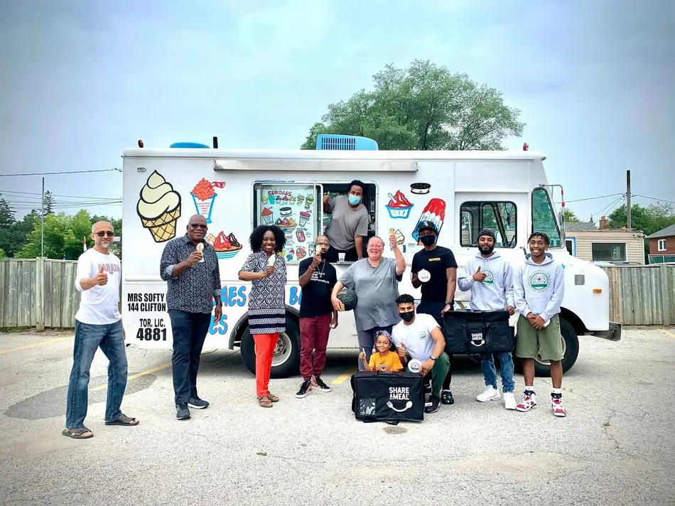 Good Guides mentors and community members gathered at an ice-cream truck with Share-a-Meal bags at an outdoor event in Scarborough