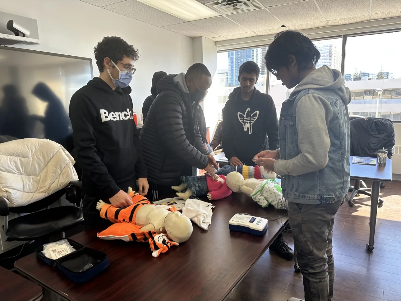 Young people practising infant CPR on training manikins at a table during a first aid training session